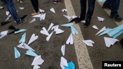 People stand next to paper planes, symbol of Telegram messenger, released during a rally in protest against court decision to block the messenger because it violated Russian regulations, in Moscow, April 30, 2018. 