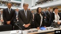 Delegate stands for a minute of silence in memory of the deceased health workers at the World Health Organization (WHO) assembly, May 18, 2015, Geneva. 