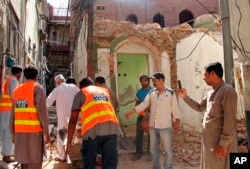 FILE - Pakistani volunteers collect debris from an Ahmadi mosque demolished by an angry mob, in the eastern city of Sialkot, May, 24, 2018.