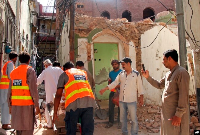 FILE - Pakistani volunteers collect debris from an Ahmadi mosque demolished by an angry mob, in the eastern city of Sialkot, May, 24, 2018.
