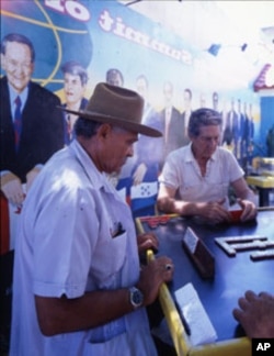 Men play dominoes next to a mural depicting the first Summit of the Americas, at which leaders of 34 North, Central and South American nations gathered in Miami in 1994.