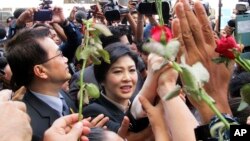 Mantan PM Thailand Yingluck Shinawatra (tengah) berjalan melewati para pendukungnya saat meninggalkan Mahkamah Agung Thailand di Bangkok (19/5).