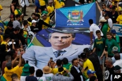 People hold a banner with a photo of Brazil's former army captain Jair Bolsonaro before the swearing-in ceremony, in front of the Planalto palace in Brasilia, Jan. 1, 2019.