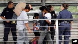 FILE - In this June 21, 2018, photo, Ever Castillo, left, and his family, immigrants from Honduras, are escorted back across the border by US Customs and Border Patrol agents in Hildalgo, Texas. 