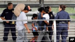 FILE - In this June 21, 2018, photo, Ever Castillo, left, and his family, immigrants from Honduras, are escorted back across the border by US Customs and Border Patrol agents in Hildalgo, Texas. 