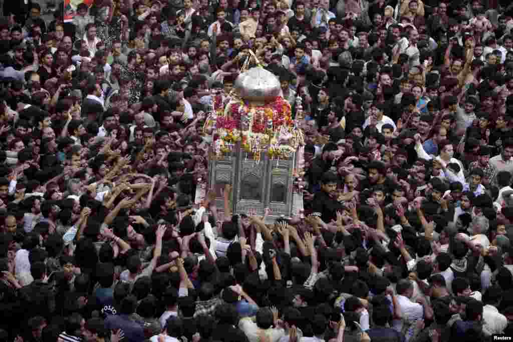 Shi&#39;ite Muslims reach out to touch a model of the Tomb of Imam Ali Ibn Abu Talib, son-in-law of Prophet Mohammad, during the religious procession of Yaum-e-Ali, which marks the death anniversary of Imam Ali in Lahore, Pakistan. &nbsp;