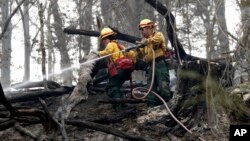 Firefighters Valarie Lopez, left, and Mark Tabaez work to cool hot spots after a wildfire burned a hillside in Clayton, Georgia, Nov. 15, 2016, 