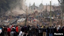 Onlookers watch as bulldozers demolish houses to make way for a new road in the Kibera slum in Nairobi, Kenya, July 23, 2018.