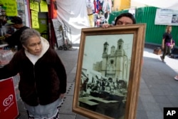 Rosa Maria Ubaldo Lopez looks at an 1910 photograph of her neighborhood, where the oldest building is located in Mexico City, Sept. 10, 2018.