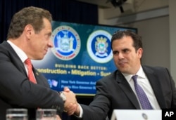 Gov. Andrew Cuomo, left, and Puerto Rico Gov. Ricardo Rossello shake hands at a news conference, Nov. 2, 2017, in New York. Cuomo announced that the state will be sending personnel and trucks to aid in the reconstruction of Puerto Rico's electrical grid.