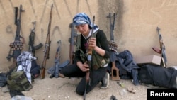 A Kurdish female fighter from Kurdish People's Protection Units [YPG] checks her weapon near Ras al-Ain, in the province of Hasakah, after capturing it from Islamist rebels, November 6, 2013.