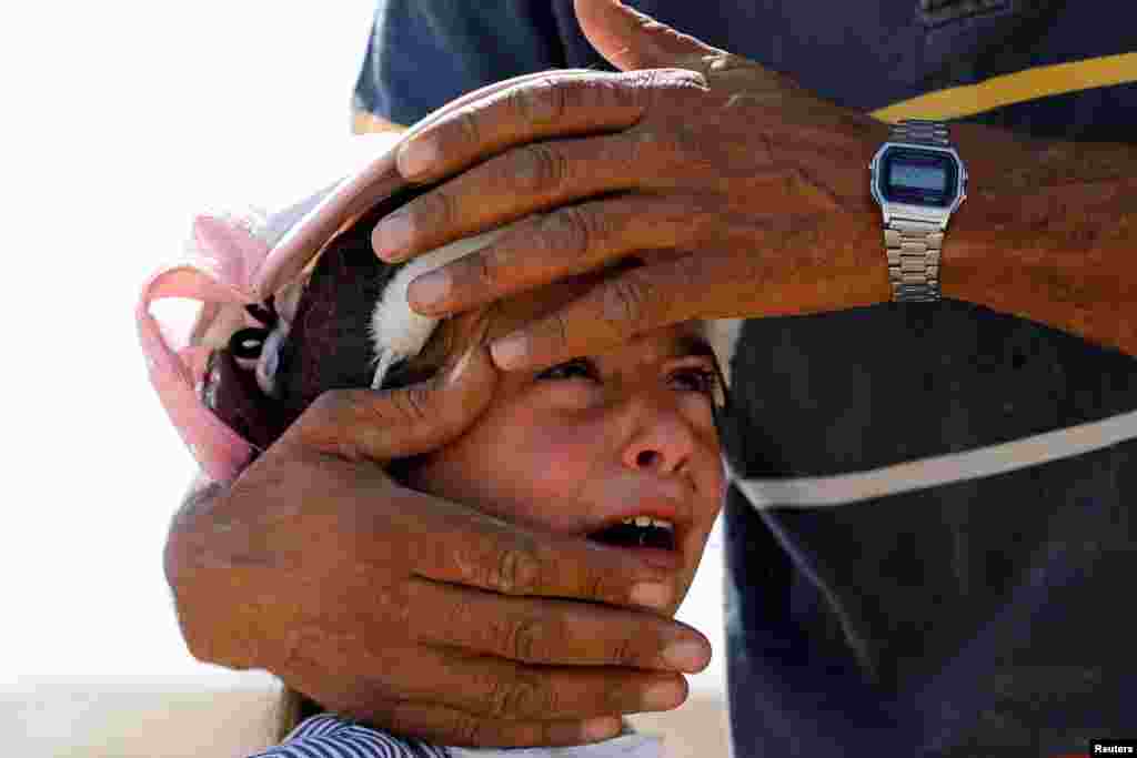 A Palestinian girl cries as she is comforted by her uncle after Israeli forces demolished her family&#39;s house near Hebron in West Bank.