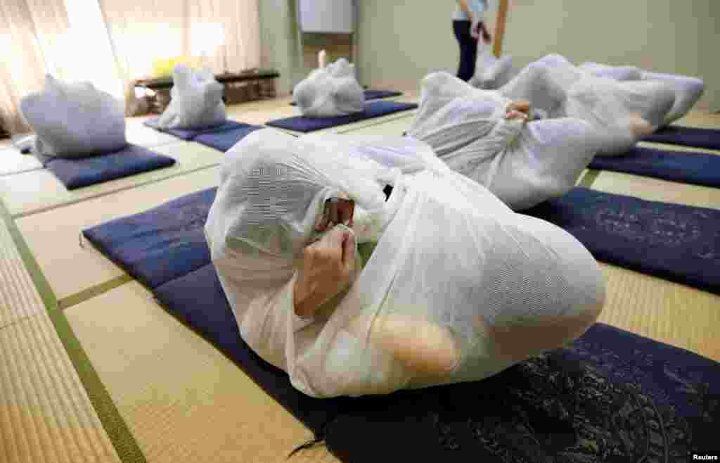 Participants perform Otonamaki, which translates as &quot;adult wrapping&quot;, a new form of therapy where people are wrapped in large swaddling cloth to alleviate posture problems and stiffness, at a session in Asaka, Saitama prefecture, Japan, Feb. 4, 2017.