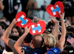 Supporters for Democratic presidential candidate Hillary Clinton hold up campaign logos during a presidential primary election night rally in New York, June 7, 2016..