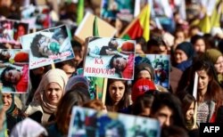 FILE - Syrian Kurds wave banners and placards during a demonstration in Qamishli, Jan. 20, 2019, marking the first anniversary of the takeover of the northern Syrian city of Afrin by the Turkish army and Turkish-backed Syrian rebels.