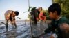 Seorang laki-laki bernama Samsudin sedang menanam pohon-pohon bakau bersama anak-anak di Pantai Tiris, Desa Pabeanilir, Kabupaten Indramayu, Jawa Barat, 11 Maret 2021. (Foto: Willy Kurniawan/Reuters)