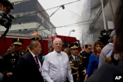 Peru's President Pedro Pablo Kuczynski walks to inspect firefighting efforts at a warehouse in Lima, Peru, June 23, 2017.