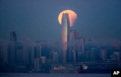 A partially-eclipsed super blue blood moon sets behind the Salesforce Tower, Jan. 31, 2018, in San Francisco, California.