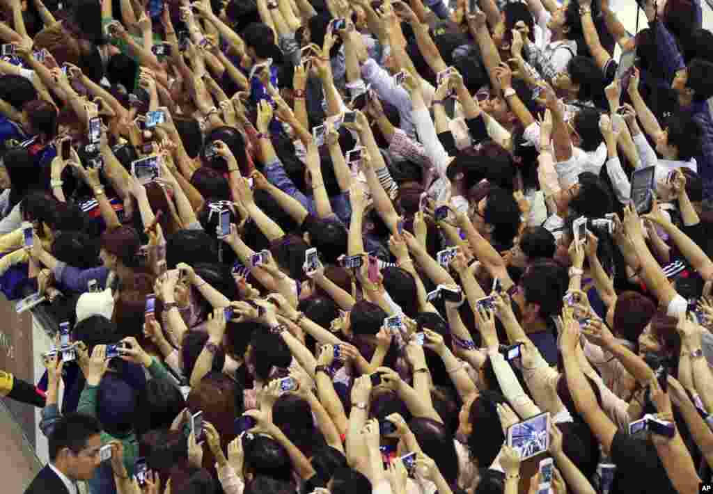 Fans of Japanese national soccer team try to take pictures of players as they return from Brazil to home country at Narita International Airport in Narita, near Tokyo. 