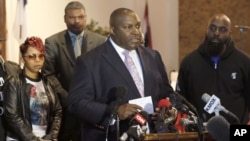 Attorney Daryl Parks, center, talks to reporters on behalf of Michael Brown's parents, Lesley McSpadden, left, and Michael Brown Sr., right, at a news conference in Dellwood, Mo., March 5, 2015.