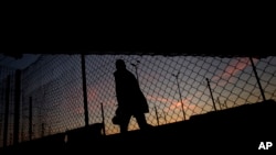 FILE - A migrant is seen walking after crossing a fence as he attempts to access the Channel Tunnel in Calais, northern France. The new controls will be part of larger security measures around the climate conference 