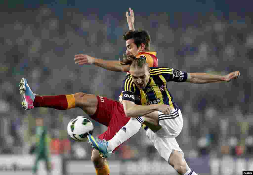 Caner Ertekin (dir.) do Fenerbahce luta pela bola com Aydin Yilmaz do Galatasaray durante o jogo da Super Liga Turca no estádio Sukru Saracoglu em Istambul (12 Maio)