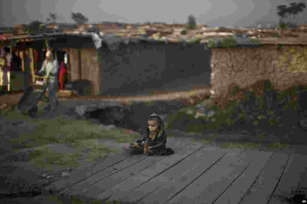 An Afghan refugee child sits on roadside in a poor neighborhood on the outskirts of Islamabad, Pakistan.