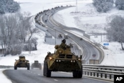 FILE - A convoy of Russian armored vehicles moves along a highway in Crimea, Jan. 18, 2022.