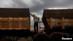 Un conductor de camión brasileño se cubre el rostro para protegerse del polvo mientras espera para entregar su carga de granos en el estado Mato Gross, Brasil, en el 2012.