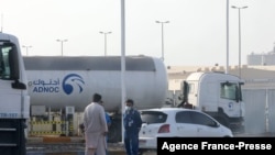 Men stand outside a storage facility of oil giant ADNOC in the capital of the United Arab Emirates, Abu Dhabi, Jan. 17, 2022. Three people were killed in a suspected drone attack that set off a blast and a fire in Abu Dhabi, officials said.