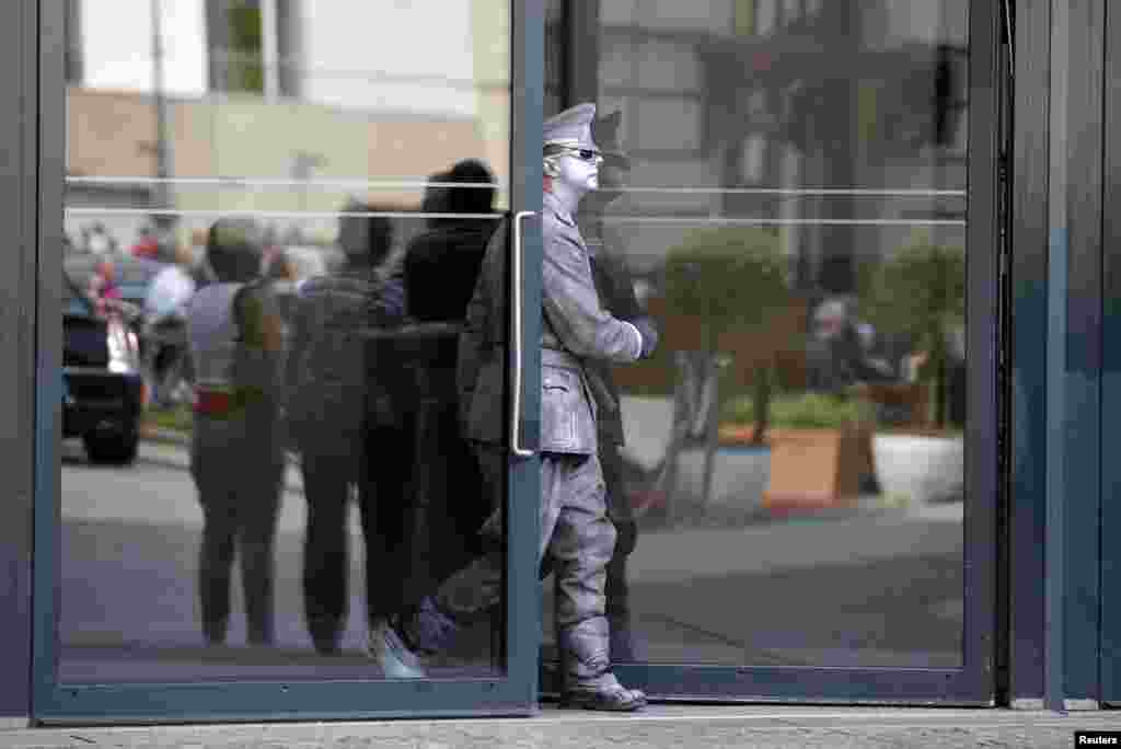 A street artist wearing a colored uniform of the former East German army leaves the Academy of Arts near the Brandenburg Gate in Berlin.