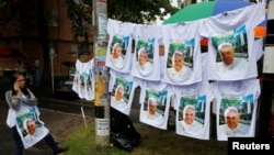 A woman sells T-shirts with images of Pope Francis as the faithful arrive for a holy mass Saturday by Pope Francis outside Olaya Herrera Airport, Medellin, Colombia, Sept. 8, 2017.
