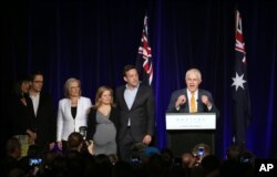 Australian Prime Minister Malcolm Turnbull (r) addresses party supporters as his family listen from his side during a rally in Sydney on July 3, 2016, following a general election.