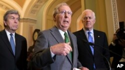 FILE - Senate Majority Leader Mitch McConnell, R-Ky., flanked by Sen. Roy Blunt, R-Mo., left, and Majority Whip John Cornyn, R-Texas, speaks to reporters, Nov. 7, 2017.