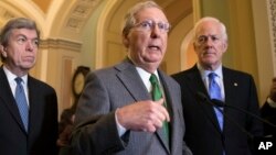 FILE - Senate Majority Leader Mitch McConnell, R-Ky., flanked by Sen. Roy Blunt, R-Mo., left, and Majority Whip John Cornyn, R-Texas, speaks to reporters, Nov. 7, 2017.