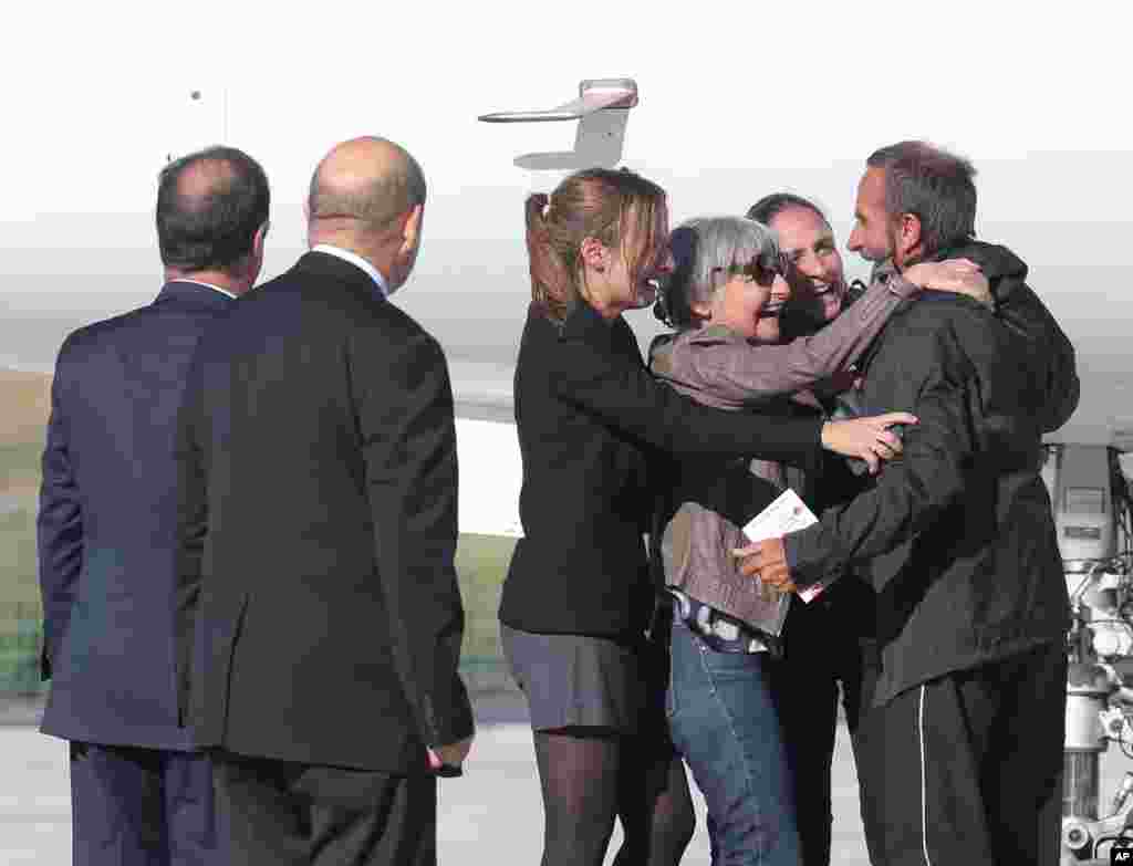 Released French hostage Daniel Larribe, right, is surrounded by his wife and two daughters as President Francois Hollande, left, and Defense Minister Jean-Luc Le Drian, second left, look on after Larribe's arrival at Villacoublay military airbase, outside Paris. The four Frenchmen were held hostage in the Sahara desert by al-Qaida-linked gunmen for three years.