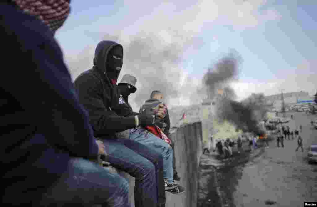 Demonstran Palestina duduk di atas tembok penghalang kontroversial Israel yang memisahkan kota Abu Dis dan Yerusalem di Tepi Barat.