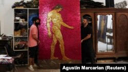 Argentine artist Marcelo Toledo (R) and his assistant Facundo Mineldin shift an art piece depicting Adam, which will be part of the "Museum of the After", at his workshop in Buenos Aires, Argentina March 4, 2021. (REUTERS/Agustin Marcarian)