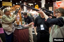 FILE - Kathy Hansen, right, tests a Trijicon rifle scope at the Safari Club International Convention in Reno, Nevada, Jan. 29, 2011.