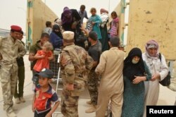 Iraqi soldiers help civilians, who fled from Falluja because of Islamic State violence, during a dust storm on the outskirts of Fallujah, Iraq, June 18, 2016