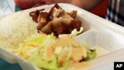 Belinda Lau, manager of the Wiki Wiki Drive Inn takeout restaurant in Honolulu, holds a polystyrene foam box containing an order of roast pork, rice and salad, March 14, 2019. 