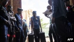 Des employés de la Commission électorale nationale indépendante (CENI) déchargent un camion de matériel de vote dans un bureau de vote alors qu'il était gardé par la police à Bukavu, le 28 décembre 2018.