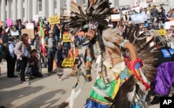 FILE - A supporter of the Bears Ears and Grand Staircase-Escalante National Monuments dances with a headdress during a rally in Salt Lake City, Dec. 2, 2017.