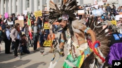 A supporter of the Bears Ears and Grand Staircase-Escalante National Monuments dances with a headdress during a rally, Dec. 2, 2017, in Salt Lake City, Utah. 