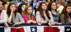 Young women listen to first lady Michelle Obama speak during a campaign rally for Democratic presidential candidate Hillary Clinton in Manchester, N.H., Oct. 13, 2016.