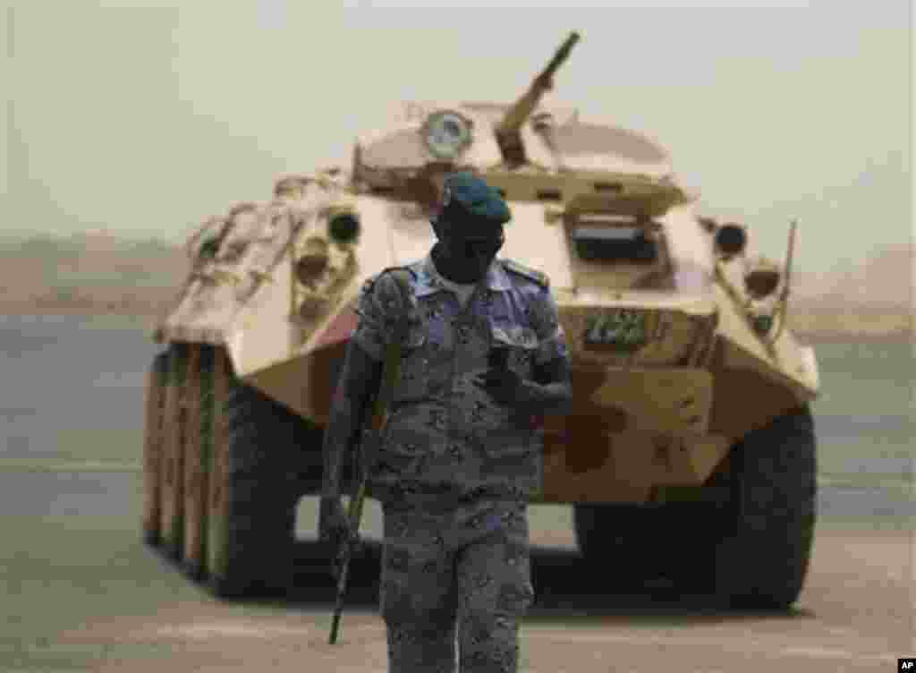 A soldier walks past an armored vehicle parked on the tarmac of the international airport, where coup leader Capt. Amadou Haya Sanogo had been due to meet a delegation of West African presidents, in Bamako, Mali Thursday, March 29, 2012.