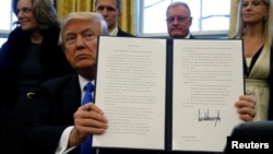 U.S. President Donald Trump holds an executive order dealing with members of the administration lobbying foreign governments, after signing it in the Oval Office at the White House in Washington, Jan. 28, 2017. 