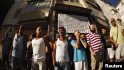 Members of 'Stop Desahucios' [Stop evictions], 15M and 'Afectados X la Hipoteca' [Mortgage Victims Platform] block the door of the building of the Lopez family's flat, before being evicted for failing to pay their mortgage, in Malaga, July 6, 2012.