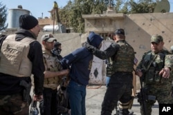 Iraqi security forces search a civilian in the city of Mosul. Security forces search the liberated eastern part of the city for suspected Islamic State group members still living in the town, Feb. 21, 2017.