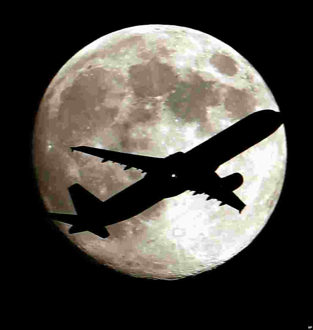 A airlines jet plane approaching Los Angeles International Airport crosses the moon as seen from Palm Park in Whittier, California, USA, Aug. 19, 2013.